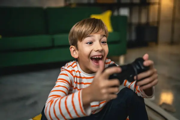 一个男孩坐在家里拿着控制杆玩游戏机 — 图库照片