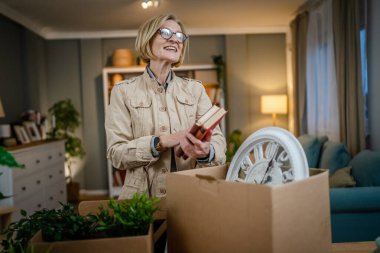 Yaşlı bir kadın emekli büyükanne yeni bir daireye taşınıyor. Eşyalarını ve bitkilerini kutulara koyuyor, paketliyor ya da boşaltıyor. Gerçek insan kitapları tutuyor.