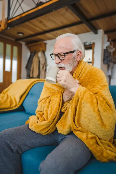 1人の白人男性シニア男性は 自宅でソファーベッドに座って お茶のコモン コールド くしゃみ病風邪をひいた — ストック写真