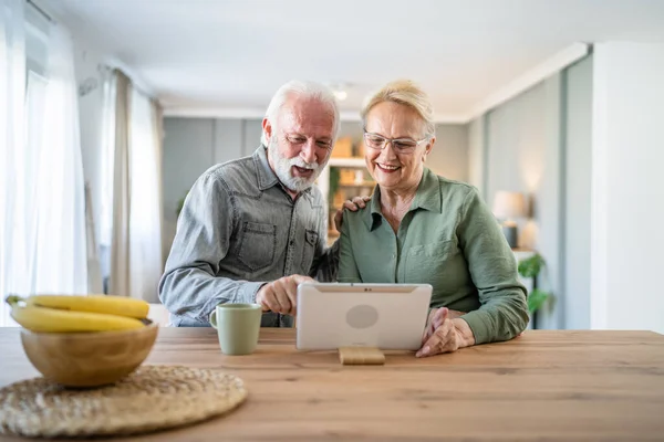 Senior couple caucasian old man and woman husband and wife pensioner grandfather and grandmother use digital tablet for online video call at home in bright room real people family concept copy space