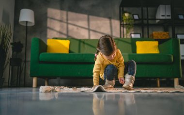 girl toddler child puts on her own boots in the winter at home