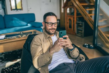 Beyaz, sakallı ve evde yaşayan bir erkek cep telefonu kullanarak SMS mesajları, internet ve video arama uygulamaları kullanıyor.