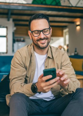 Beyaz, sakallı ve evde yaşayan bir erkek cep telefonu kullanarak SMS mesajları, internet ve video arama uygulamaları kullanıyor.