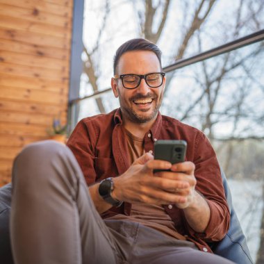 Beyaz, sakallı ve evde yaşayan bir erkek cep telefonu kullanarak SMS mesajları, internet ve video arama uygulamaları kullanıyor.