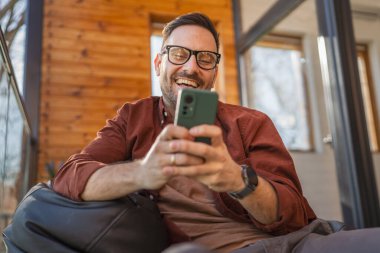 Beyaz, sakallı ve evde yaşayan bir erkek cep telefonu kullanarak SMS mesajları, internet ve video arama uygulamaları kullanıyor.