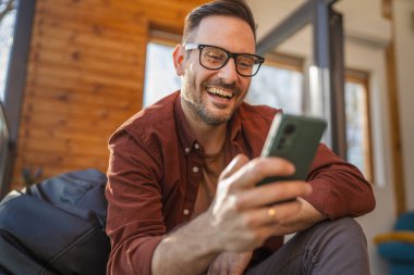 Beyaz, sakallı ve evde yaşayan bir erkek cep telefonu kullanarak SMS mesajları, internet ve video arama uygulamaları kullanıyor.