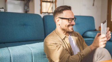 Yetişkin bir beyaz erkek dijital tablet işi yapıyor ya da internette mutlu bir gülümseme takınıyor. Her sabah kendine güvenen, rutin fotokopi çeken gerçek bir insan.