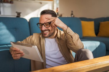 Yetişkin bir beyaz erkek dijital tablet işi yapıyor ya da internette mutlu bir gülümseme takınıyor. Her sabah kendine güvenen, rutin fotokopi çeken gerçek bir insan.