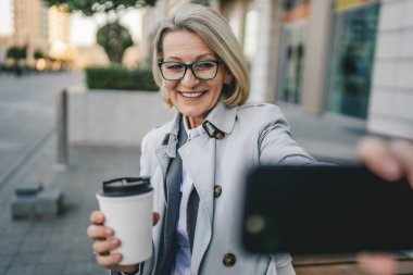 Yetişkin bir kadın cep telefonuyla fotoğraf ya da video çekiyor.