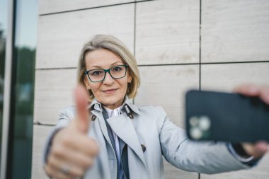 Yetişkin bir kadın cep telefonuyla fotoğraf ya da video çekiyor.