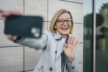 Yetişkin bir kadın cep telefonuyla fotoğraf ya da video çekiyor.