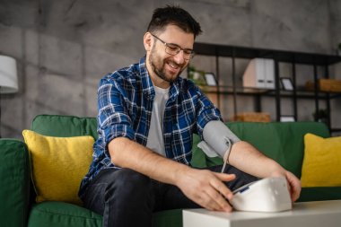 Man caucasian male sit at the table at home check measure blood pressure real person health care concept