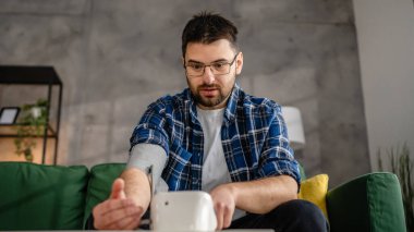 Man caucasian male sit at the table at home check measure blood pressure real person health care concept
