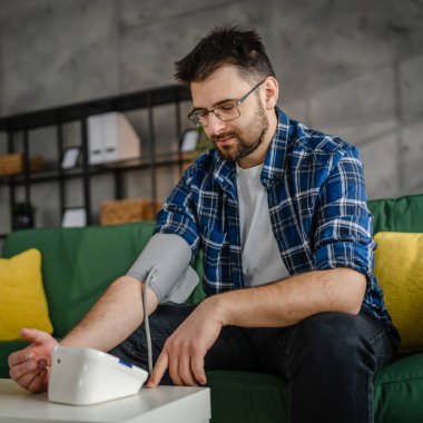 Man caucasian male sit at the table at home check measure blood pressure real person health care concept