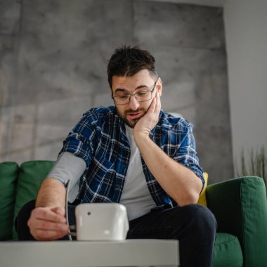 Man caucasian male sit at the table at home check measure blood pressure real person health care concept