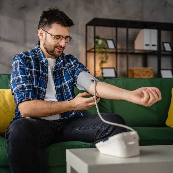 stock image Man caucasian male sit at the table at home check measure blood pressure real person health care concept