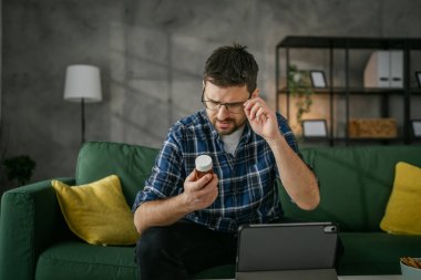 One man hold medicine drugs bottle pills read label on digital tablet