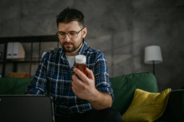 One man hold medicine drugs bottle pills read label on digital tablet
