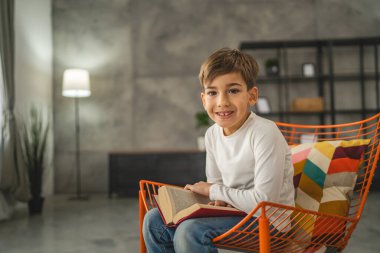 Kafkasyalı bir çocuk, yedi yaşında bir çocuk evde kitap okuyor.