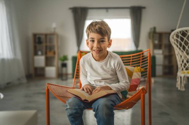 Kafkasyalı bir çocuk, yedi yaşında bir çocuk evde kitap okuyor.