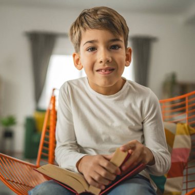 Kafkasyalı bir çocuk, yedi yaşında bir çocuk evde kitap okuyor.
