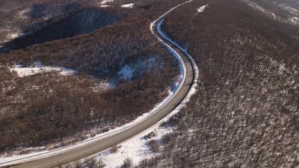 旅行の輸送と休暇のコンセプトセルビアのKnjazevac近くの冬の日に白い雪と山の範囲で道路上の高角度の空中ビュードローンビデオ誰も空に — ストック動画