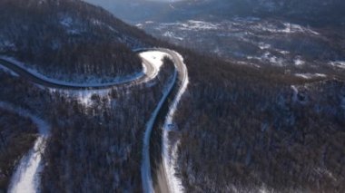 Minibüs kış günü kar altında dağ sırasındaki hava manzarasında yol alır.