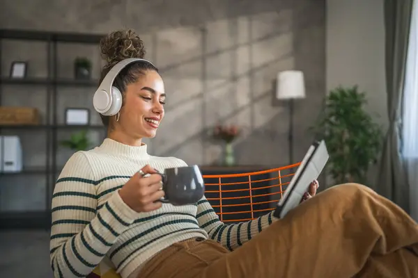 Genç Bir Kadın Evde Oturup Dijital Tablet Kulaklık Kullanarak Film — Stok fotoğraf