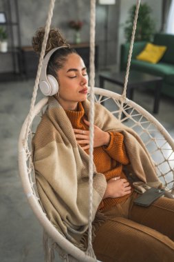 Yetişkin bir kadın Kafkas kadın milenyumu kulaklıkları online rehberli meditasyon için kullanıyor evde gözleri kapalı farkındalık yogası yapıyor gerçek insanların kişisel bakım kavramını taklit ediyor.