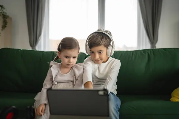 兄弟姉妹の兄弟姉妹は 家庭でデジタルタブレットを使用しています オンラインビデオを見る — ストック写真