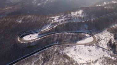 Car drive in snow winter day on the road in mountain range aerial view