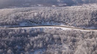 Car drive in snow winter day on the road in mountain range aerial view