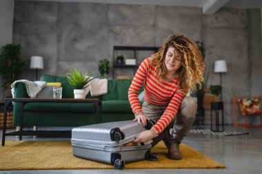 Bir kadın valizini toplayıp tatile hazırlanıyor.