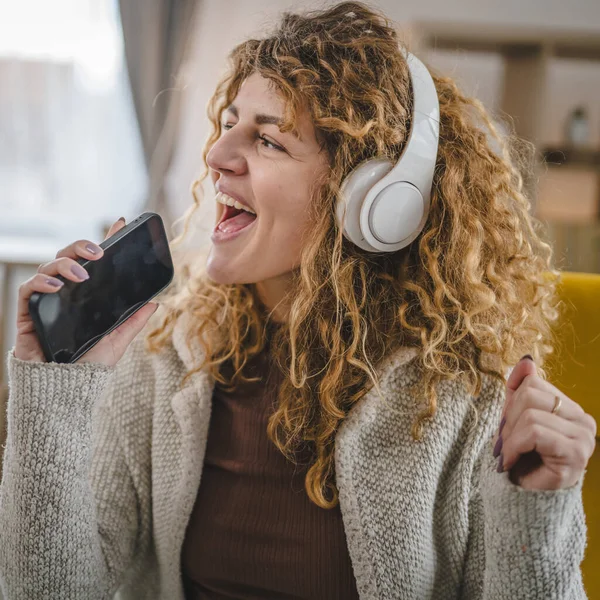 Kafkasyalı Kulaklıklı Yetişkin Bir Kadın Evde Cep Telefonu Ile Müzik — Stok fotoğraf