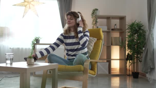 一位成年女性使用耳机进行在线引导冥想练习心神瑜珈 在家中闭上双眼真正的人自我保健概念慢动作 — 图库视频影像