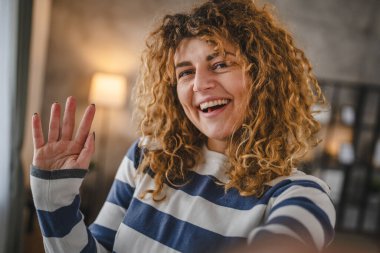 Evde kıvırcık saçlı, yetişkin beyaz bir kadının portresi. Mutlu bir gülümseme. Kendi portresi çirkin kullanıcı tarafından oluşturulmuş.