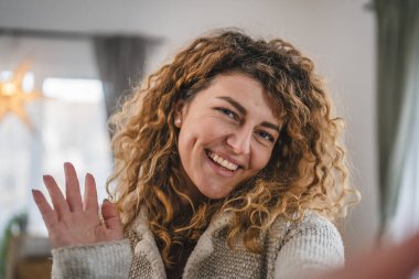 Evde kıvırcık saçlı, yetişkin beyaz bir kadının portresi. Mutlu bir gülümseme. Kendi portresi çirkin kullanıcı tarafından oluşturulmuş.