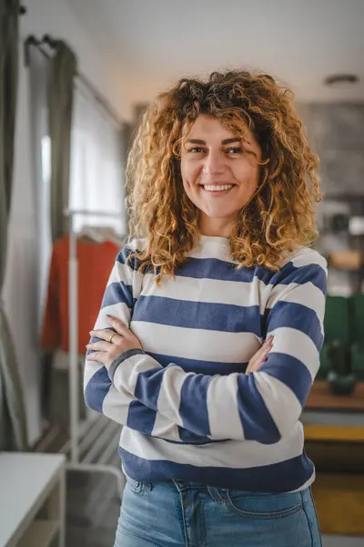 Evde kıvırcık saçlı, mutlu gülümseyen yetişkin beyaz kadın portresi.