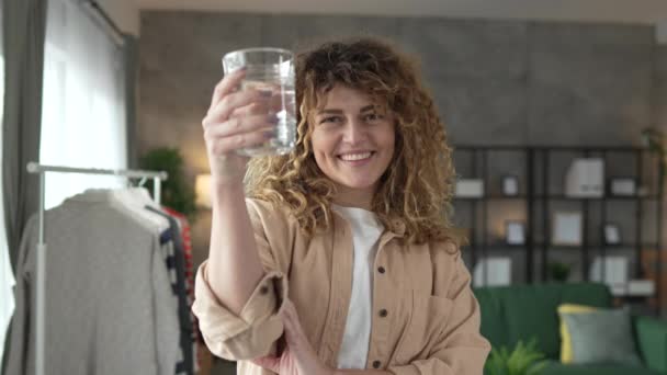 一位女士美丽的成年女性与一杯水卷发快乐的微笑健康的生活方式水合物的概念 — 图库视频影像