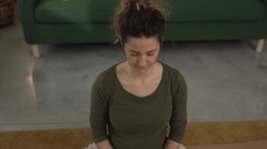 Yetişkin bir kadın Kafkas kadın milenyumu kulaklıkları online rehberli meditasyon için kullanıyor evde gözleri kapalı farkındalık yogası yapıyor gerçek insanlar özbakım kavramı yavaş çekim