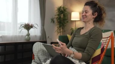 Evde mutlu gülümseyen yetişkin bir kadın banka kartı ve dijital tablet alışverişi e-bankacılık konseptini tutuyor. Gerçek insanlar uzay e-ticaretini kopyalıyor ya da rezervasyon yaptırıyor.