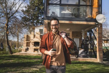 Evinde seyahat çantası taşıyan mutlu bir beyaz adamın portresi.