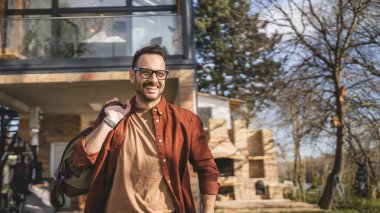 Evinde seyahat çantası taşıyan mutlu bir beyaz adamın portresi.