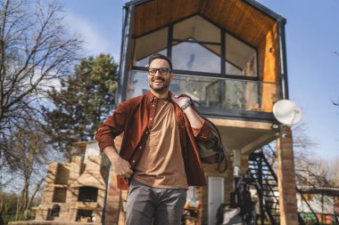 Evinde seyahat çantası taşıyan mutlu bir beyaz adamın portresi.