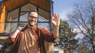 Evinde seyahat çantası taşıyan mutlu bir beyaz adamın portresi.
