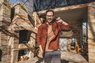 Evinde seyahat çantası taşıyan mutlu bir beyaz adamın portresi.