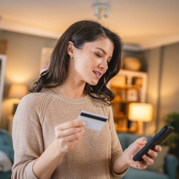 Одна женщина взрослая белая женщина дома счастливая улыбка держать банковскую кредитную карту и цифровой планшет онлайн покупки концепции электронного банкинга реальные люди копируют пространство электронной коммерции сделать покупку или бронирование