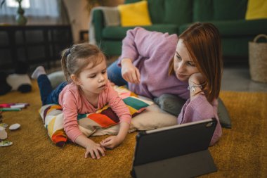 Anne ve kızı evde online video izlemek için dijital tablet kullanıyorlar.