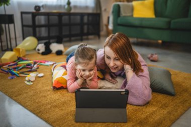 Anne ve kızı evde online video izlemek için dijital tablet kullanıyorlar.