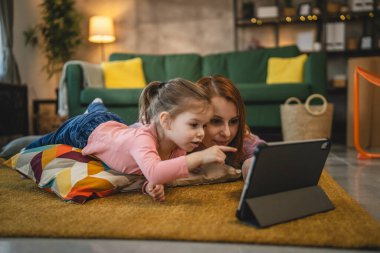 Anne ve kızı evde online video izlemek için dijital tablet kullanıyorlar.